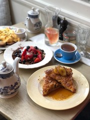 Trendy breakfast layout with french toast, granola, coffee, scrambled eggs on wooden table