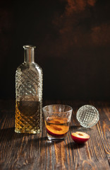 Rakia or rakija traditional Balkan fruit brandy. Plum brandy sljivovica in a glass and decanter on a wooden table and dark background. Vertical. Copyspace