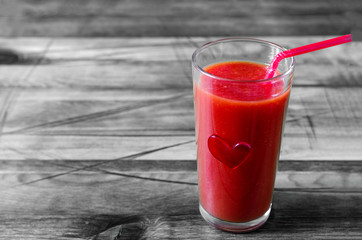 Glass with tomato juice and red heart on black and white background concept