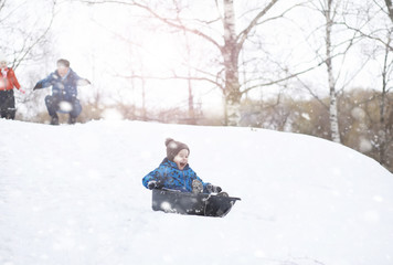 Children in the park in winter. Kids play with snow on the playground. They sculpt snowmen and slide down the hills.