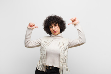 young pretty afro woman feeling proud, arrogant and confident, looking satisfied and successful, pointing to self
