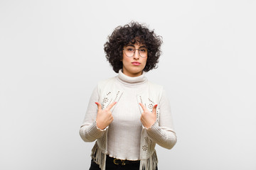 young pretty afro woman pointing to self with a confused and quizzical look, shocked and surprised...