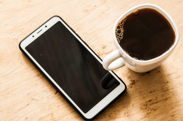 Fototapeta na wymiar Hot coffee and smartphone on the wooden counter bar.