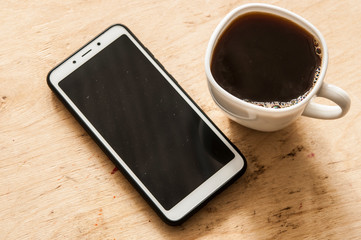 Fototapeta na wymiar Hot coffee and smartphone on the wooden counter bar.