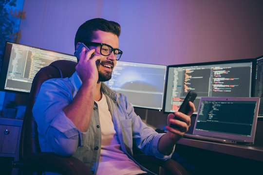 Photo Of It Specialist Guy Working Late At Night Sitting Chair Many Monitors Speaking Telephone Teammate Reading New Task In Slack Corporate Chat Night Office Indoors