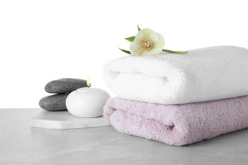 Fototapeta na wymiar Towels, spa stones and flower on marble table against white background