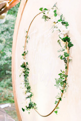 Beautiful area of the wedding ceremony. Round wooden arch, decorated with wreath from flowers, greenery. Cute, trendy rustic decor. Part of the festive decor, floral arrangement.