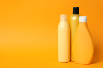 Bottles of shampoo on orange background, space for text. Natural cosmetic products