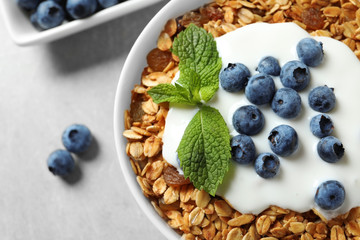 Delicious yogurt with granola and blueberries in bowl on grey table, top view