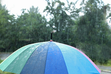 Open colorful umbrella outdoors on rainy day