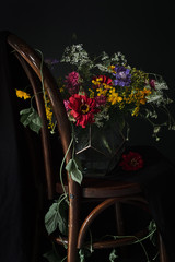 Colorful bouquet on a wooden chair on a black background