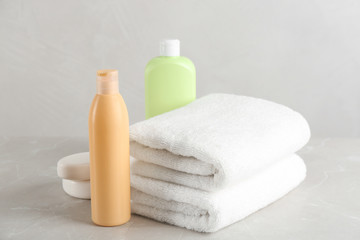 Fototapeta na wymiar Fresh towels and toiletries on light grey marble table