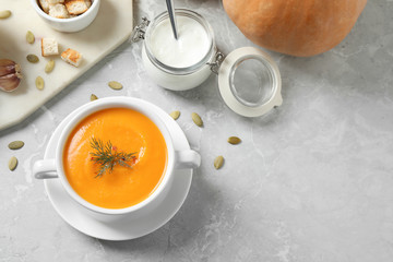 Delicious pumpkin soup in bowl on marble table, flat lay