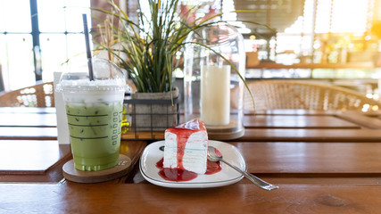 Green tea and cake on the table with background, grass and candles in orange light.
