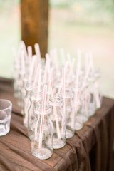 Bottles for lemonade on the wooden table outdoors. Set of glass bottles for lemonade and cocktails. Catering, wedding reception concept.