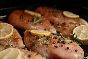 Chicken breasts with lemon and rosemary on baking sheet, closeup
