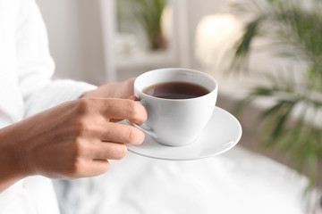 Woman with cup of hot tea at home, closeup