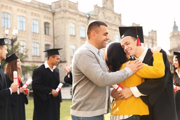Happy student with parents after graduation ceremony outdoors