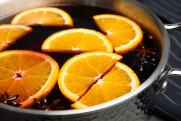 Tasty mulled wine with spices in cooking pot, closeup