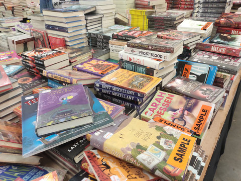 KUALA LUMPUR, MALAYSIA -JULY 07, 2019: Books on the table for sale in the huge warehouse. All books are grouped and segregated by title and genre to facilitate customers.