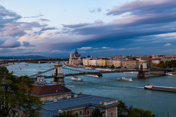 Evening twilight aerial panorama of Budapest with Chain Bridge and Parliament buliding and river boats on Danube river.