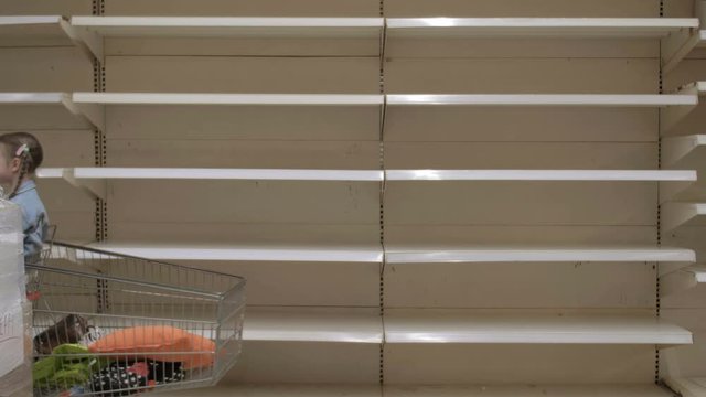 Young woman and child with trolley in shop with empty shelves