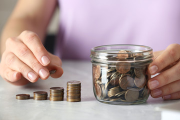 Woman stacking coins at grey marble table, closeup. Money savings
