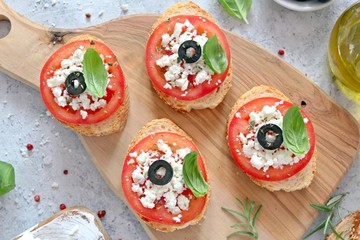 Italian tomato and cheese bruschetta. Top view with copy space. Canape with tomato, cheese, olive and basil.