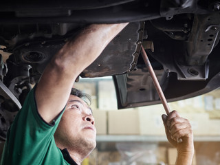 Auto mechanic working underneath car lifting machine at the garage. Auto repair shop, Car service, repair. 