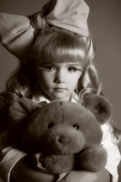 girl child blonde doll look with a big bow and a teddy bear