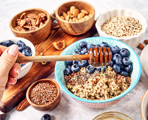 healthy breakfast, quinoa porridge with blueberries, nuts, seeds and superfoods