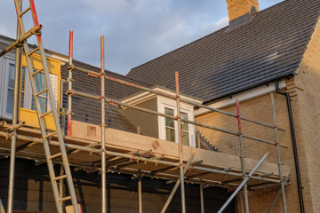 Scaffolding seen assembled around residential houses being built at a former RAF base, showing various health and safety measures imposed.