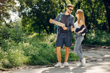 Obraz premium Tourists in a summer forest. Couple with a map.