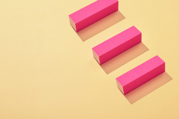 Three pink nail buffer block on yellow background