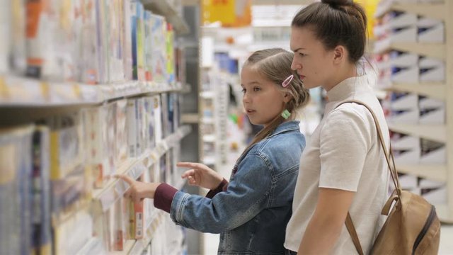 A woman with a daughter in a supermarket chooses stationery for school. Purchase of school supplies