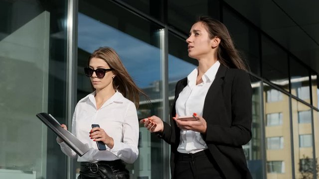 Two Young Businesswomen Walking Down The Street And Talking.