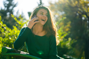 Young happy woman talking on the phone outdoor in a park.