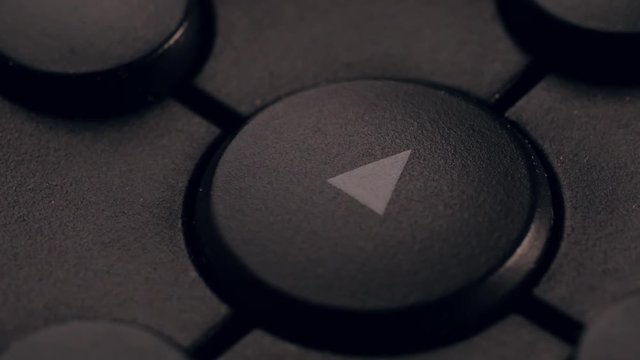 Buttons play, rewind, fast forward, stop. Angled macro shot. Slightly dark lighting.