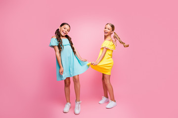 Full length photo of two funny small school ladies models rejoicing summer holidays best pupil party dancing wear bright blue yellow dresses isolated pink color background