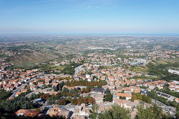 Obraz premium Republic of San Marino. Top view to the suburbs and the Rimini city and Adriatic sea in a distance