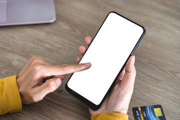 Women hands holding Mobile Phone with blank screen and Credit Card on office desk and using mobile phone for Online Shopping, Internet Banking, Online Trading, E Commerce Concept. with clipping path