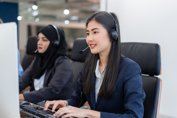 Happy smiling operator asian woman customer service agent with headsets working on computer in a...