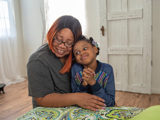African American mother and daughter pray by bed