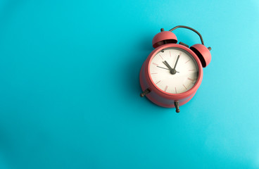 Creative flat lay concept top view of  pink vintage alarm clock on bright blue turquoise square color paper background with copy space in minimal style, template