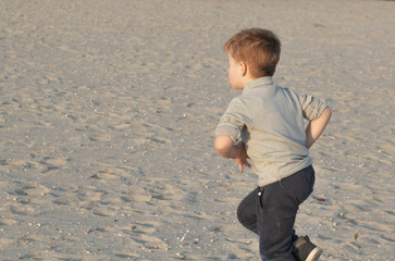 Little kid boy running on sand at the beach