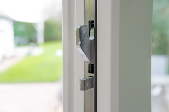 Cose-up, Shallow Focus Of A High-security Latching System Seen On A Newly Installed Double Glazed Door. A Large, Out Of Focus Garden Can Be Seen In The Background.