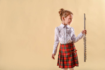 Girl Playing Silver Flute. before the concert. On a bright yellow background. In a white shirt and red skirt. Love for music. © irishasel