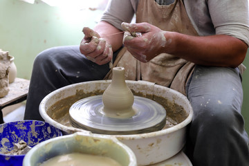 Male hands working on a potter wheel closeup. Making dishes from clay.	