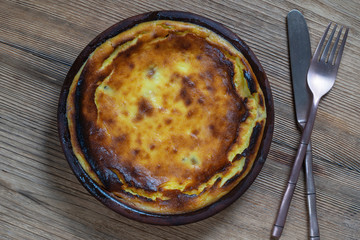 Sweet cottage cheese casserole with raisins and semolina on wooden table. Ceramic bowl with baked cottage cheese casserole , closeup, top view