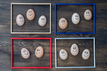 Picture frame and many funny eggs smiling on dark wooden wall background. Eggs family emotion face portrait. Concept funny food
